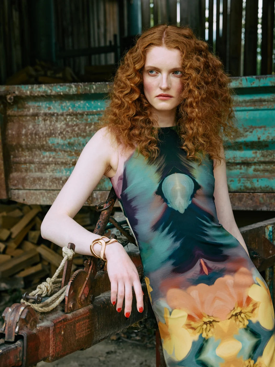 Model trägt ärmelloses Etuikleid mit abstraktem Blumenprint in Grün, Türkis, Gelb und Orange, Vorderansicht.