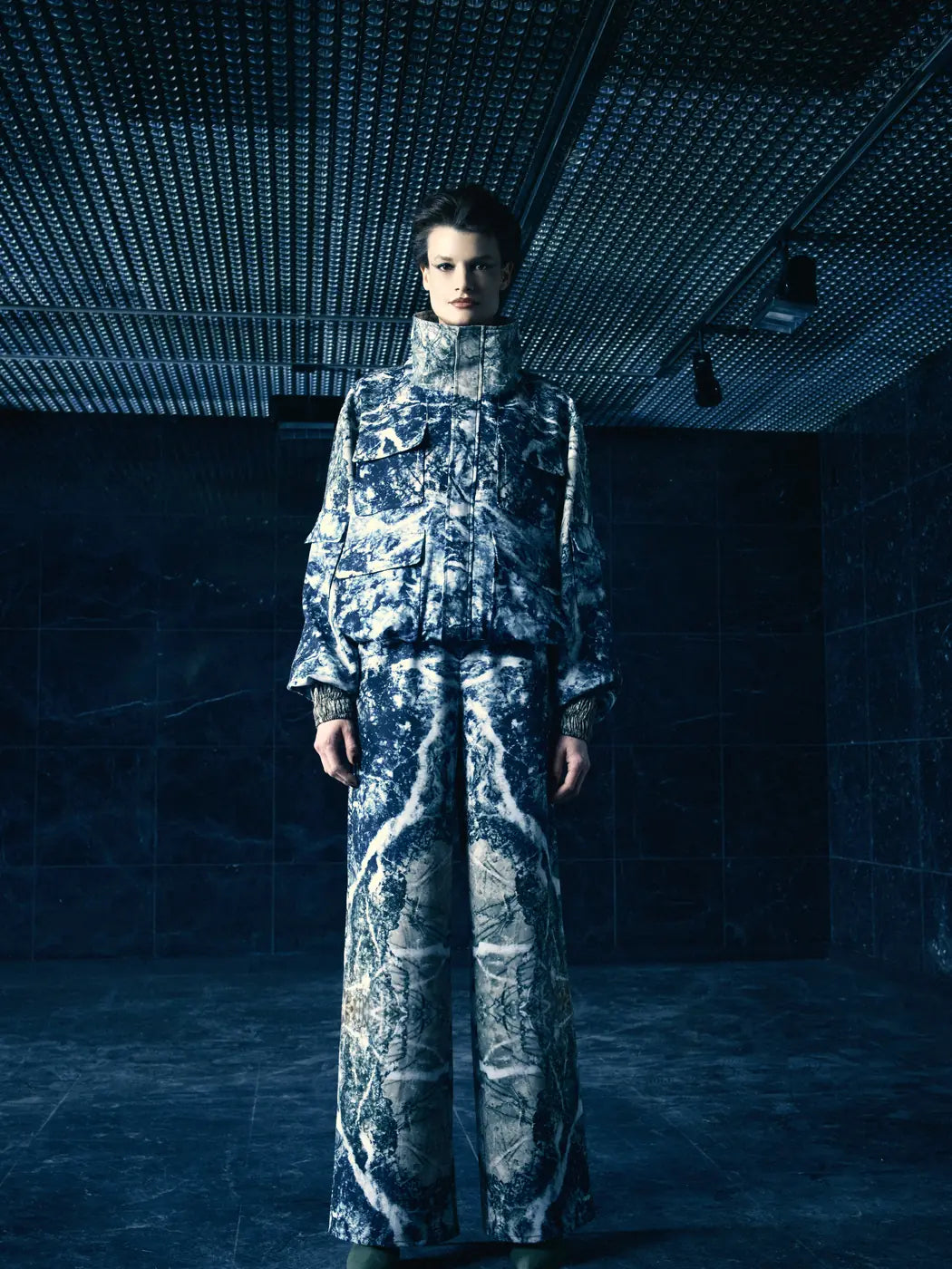 Model trägt Damen-Hose mit weitem Bein und elastischen Bund, Marmor-Print in Multicolor mit Schwarz, Weiss und Grau. Dazu passende Bomberjacke, Vorderansicht.