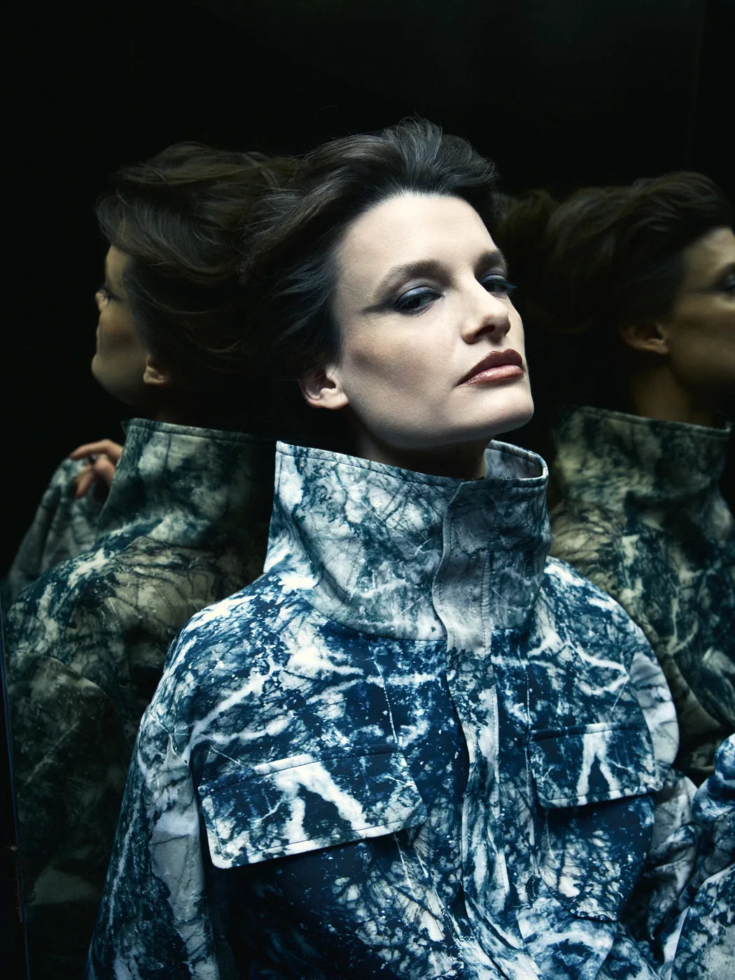 Weibliches Model trägt Unisex-Bomberjacke mit hohem Stehkragen und Marmor-Print in Schwarz, Weiss, Grau und Petrol, große aufgesetzte Taschen, Vorderansicht.
